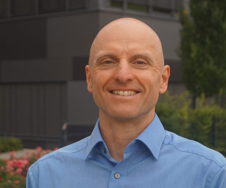 Dr. Markus Koschorreck vor einem modernen Bürogebäude.