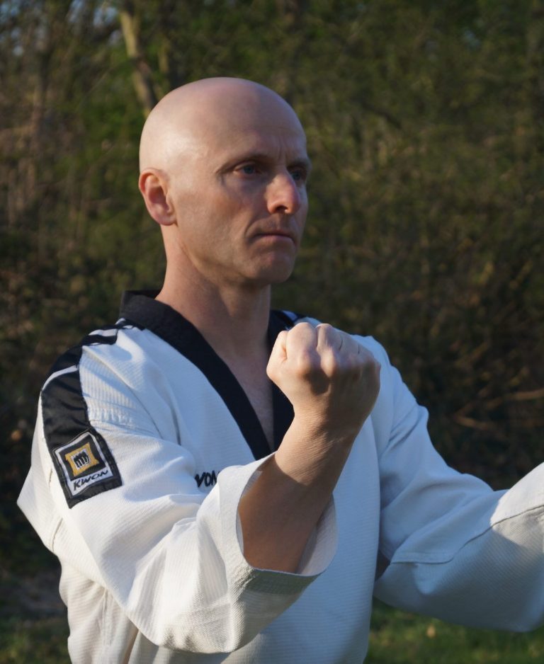Markus Koschorreck im Taekwondo-Anzug mit schwarzem Kragen führt einen Doppelblock aus.