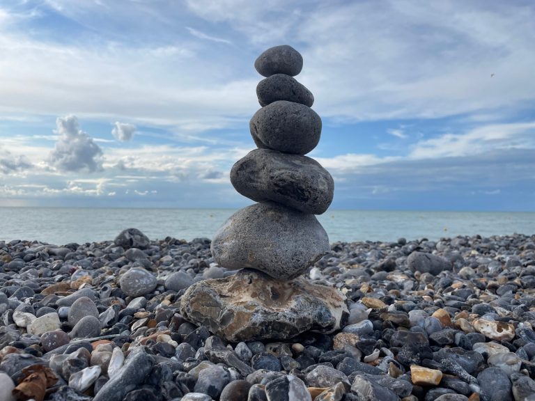 Gestapelte Steine in unterschiedlichen Größen an einem Kieselstrand am Meer.
