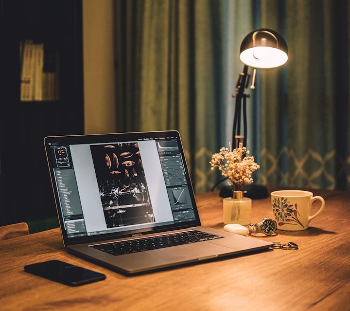 Online-Coaching Ein Laptop auf einem Tisch, daneben eine Lampe, eine Tasse und ein Smartphone.