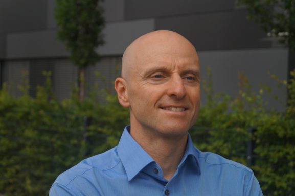 Markus Koschorreck: Portrait 2 Ein Portrait von Dr. Markus Koschorreck vor einem Bürogebäude. Seitlicher Blick.